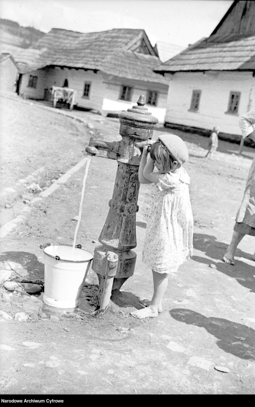 Dziewczynka czerpie wodę za pomocą ręcznej pompy, Zembrzyce,...