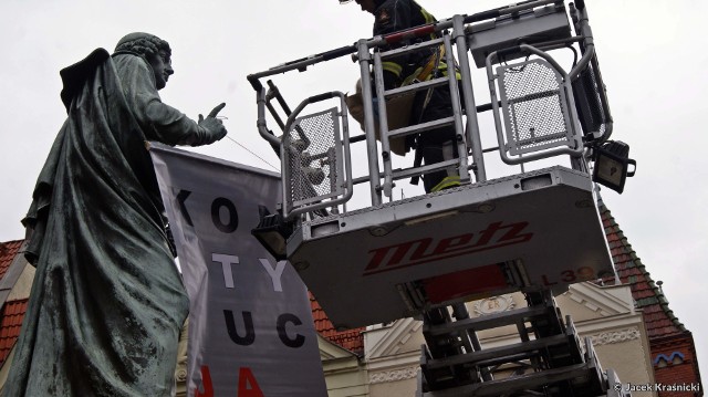 Działacze Komitetu Obrony Demokracji zawiesili dziś (15 sierpnia) na pomniku Kopernika w Toruniu transparent z napisem "KONSTYTUCJA". Podobne akcje zorganizowane były w ostatnim czasie w innych polskich miastach, w ich najbardziej rozpoznawalnych miejscach. KOD chce w ten sposób zwrócić uwagę na próby łamania konstytucji w Polsce. Po kilkudziesięciu minutach transparent zdjęła wezwana na miejsce straż pożarna.