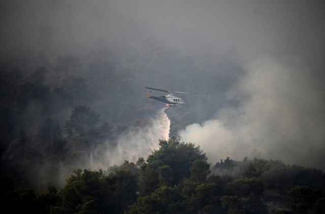 Helikopter strażacki zrzuca wodę, aby ugasić pożar, w Diakopto w Grecji