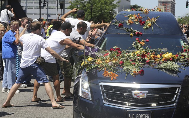 Men reach out to touch the hearse carrying the body of muhammad ali as it drives down broadway toward cave hill cemetery, tuesday, june 10, 2016, in louisville, ky. (michael clevenger/the courier-journal, pool)