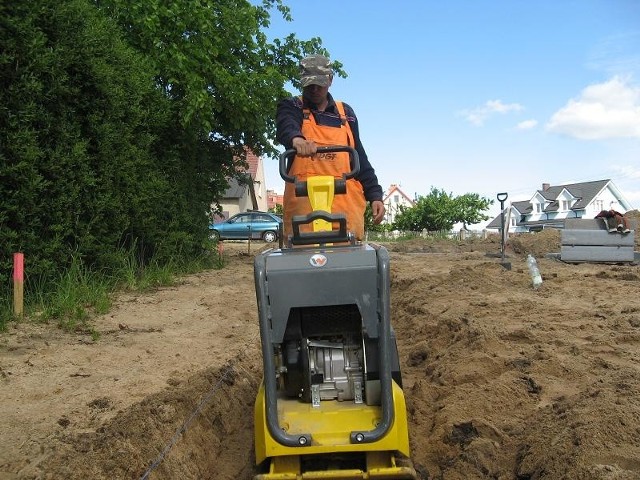 Robotnik Marek Skomorowski przygotowuje podbudowę terenu pod kładzenie kostki brukowej.