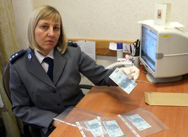 Komisarz Beata Jędrzejewska-Wrona z policji w Tarnobrzegu prezentuje zabezpieczone podróbki banknotów 50-złotowych.