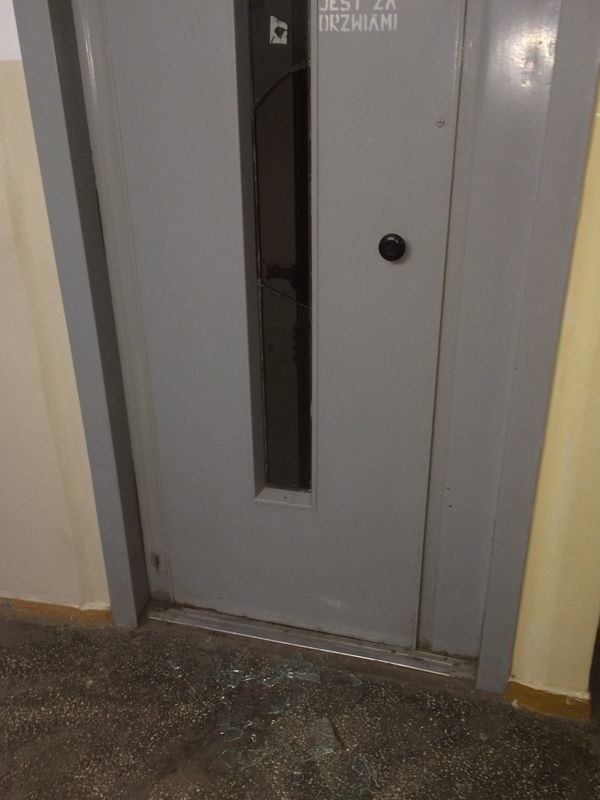 Zniszczone drzwi do windy przy ul. Romera 5. 