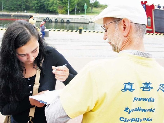 Justyna Orlik podpisuje w Kołobrzegu petycję przeciw prześladowaniom w Chinach. Petycję trzyma Jan Motyka,koordynator akcji.