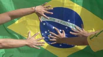 Dłonie kibiców na tle brazylijskiej flagi