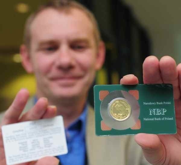 Sławomir Kusz, rzecznik opolskiego oddziału NBP, prezentuje złotą monetę bulionową.