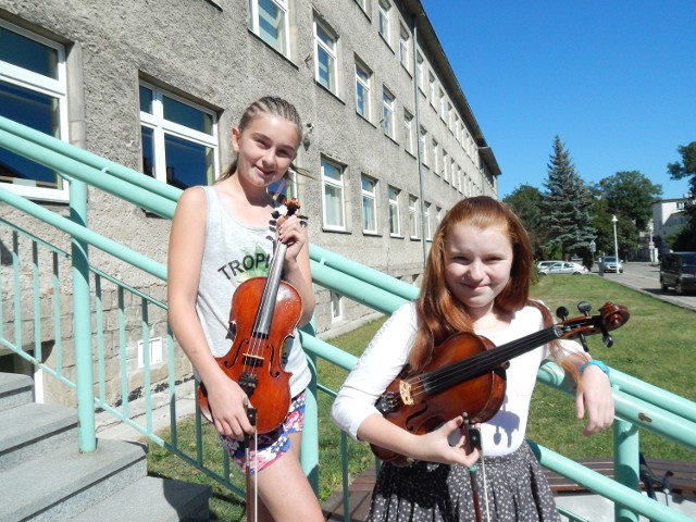 Miriam Powrósło z klasy skrzypiec PSM II st. i Małgorzata Prochota z klasy altówki PSM II st. na tle szkoły w Opolu.