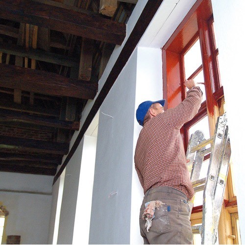 Pracownik wypożyczony przez Antoniego Krawczuka maluje okna w świątyni. Następne na liście jest malowanie ścian.