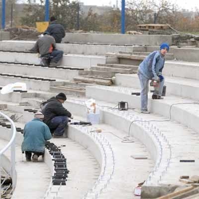 Pracownicy firmy Provena przygotowują trybuny na pierwszym wirażu do zamontowania plastikowych siedzeń