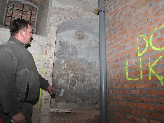 Majster Krzysztof Sodkiewicz pokazuje odkryte wejście do baszty, nową ściankę po prawej stronie trzeba będzie zburzyć, aby odsłonić przejście.