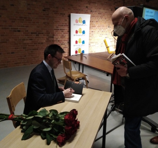 Robert Gawłowski podpisuje swoją książkę.