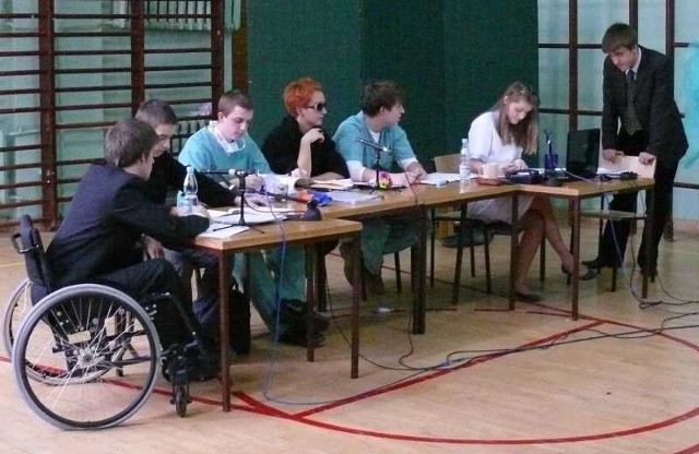Akcja sztuki dzieje się przy długim stole. Siedzą przy nim, od lewej: Arsenij Utkin (na wózku), Piotr Ludwinek, Aleksander Pasek, Diana Kosiak (reżyserka), Mikołaj Bieda, Marta Ziętara, Mikołaj Kmiecicki.