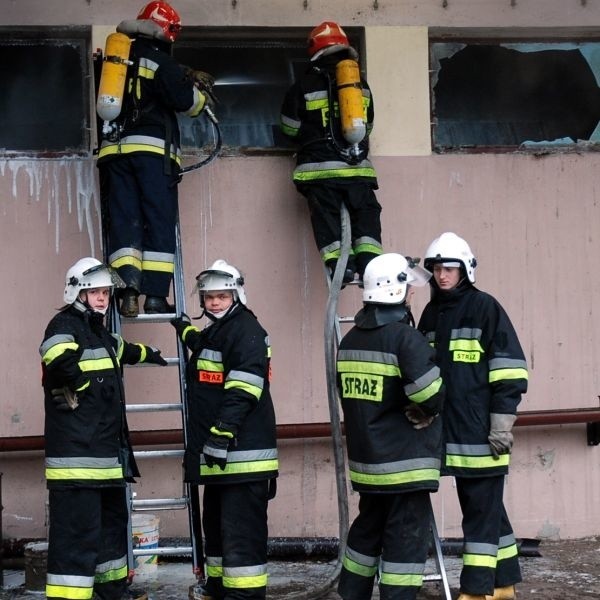 Strażacy dogaszają tlącą się okładzinę zbiornika z olejem.