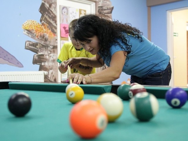 Katarzyna Szpańska, jedna z wychowawczyń, uczy 8-letniego Kubę zasad bilarda