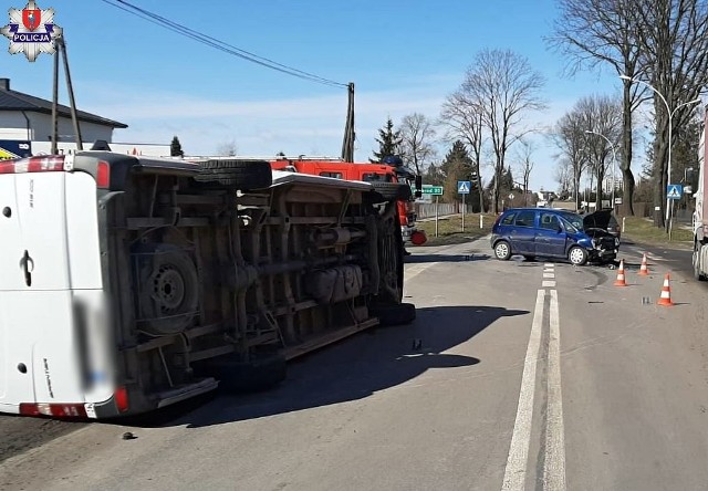 Leżący na boku bus, w oddali stojący na drodze uszkodzony opel