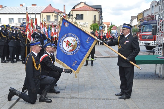 Komendant szydłowieckiej Państwowej Straży Pożarnej Krzysztof Banaszek (z prawej) przekazuje pocztowi nowy sztandar.