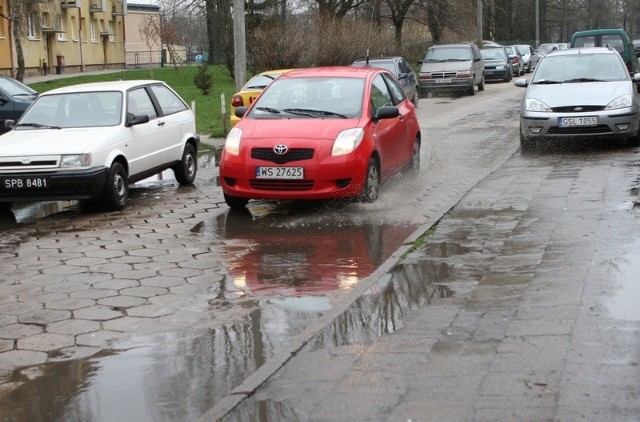 Samochody przejeżdżające przez ulicę Morcinka w czasie deszczu chlapią przechodniów.