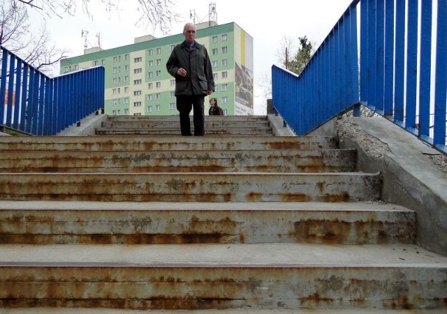 Metalowe kątowniki zamontowane w stopniach schodów prowadzących na kładkę dla pieszych nad ulicą Jana Pawła II pokrywa rdza, a z murków odpada tynk.