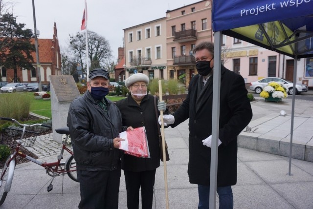 Burmistrz Kowalewa Pomorskiego Jacek Żurawski na kowalewskim rynku wręczał mieszkańcom gminy flagi narodowe oraz gminy Kowalewo Pomorskie