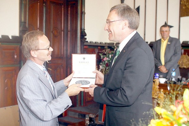 Georg Moenikes (z prawej) odbiera medal z rąk Mirosława Janowskiego, przewodniczącego Rady Miejskiej