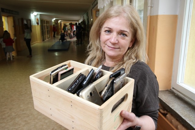 Małgorzata Świtalska pedagog z Zespołu Szkół ogólnokształcących numer 6 w Kielcach pokazuje pudełko z przegródkami do którego uczniowie wrzucają przed lekcją swoje telefony.