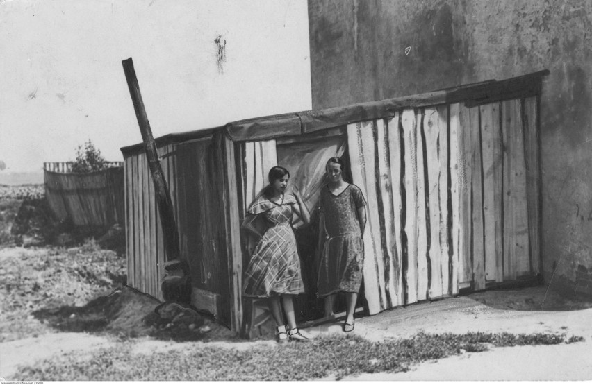 Dwie młode kobiety z bezrobotnej rodziny przed drewnianą...