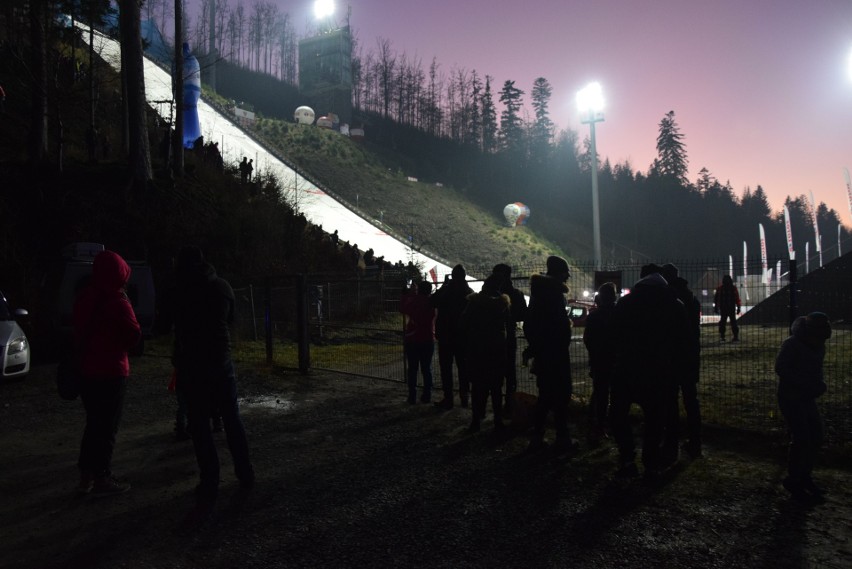 Skoki narciarskie w Wiśle. Ludzie kibicują zawodnikom zza ogrodzenia. Policja ostrzega przed mandatami