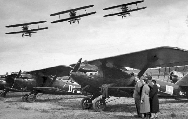 Trzy myśliwce PWS wykonują akrobacje nad stojącymi na lotnisku breguetami XIX. Katowice, 1933 r.