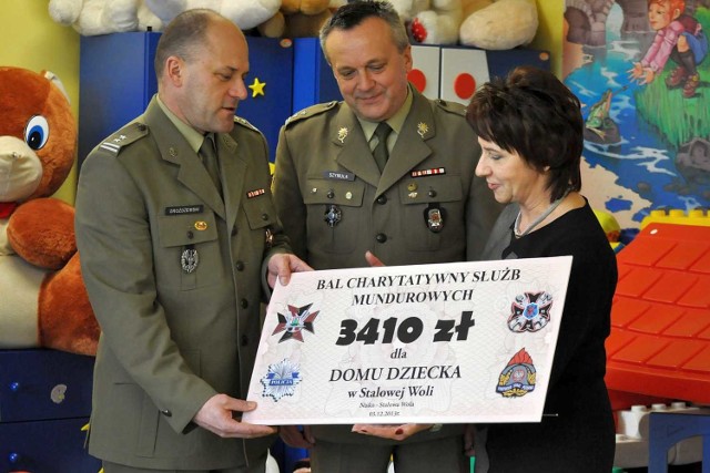 Przedstawiciele służb mundurowych przekazują symboliczny czek dyrektorce placówki Jadwidze Stępniewskiej.