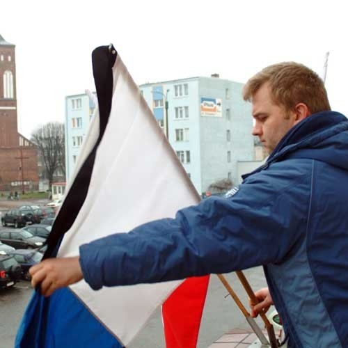 Andrzej Sokołowski zawiązuje kir przy fladze narodowej wiszącej przy budynku świdwińskiego starostwa. 