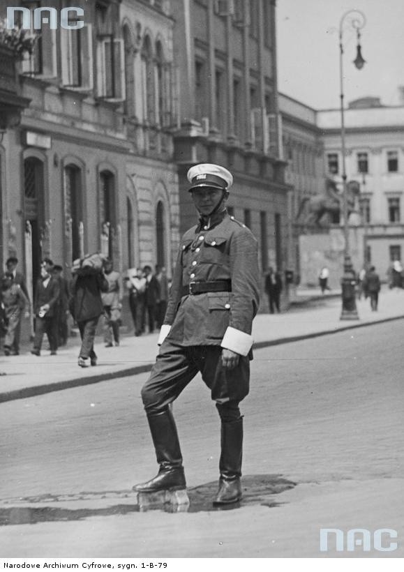 1932 r. Policjant kierujący ruchem na placu Marszałka Józefa Piłsudskiego chłodzi nogi od upału stawiając je na bloku lodowym. W głębi widoczny pomnik księcia Józefa Poniatowskiego.