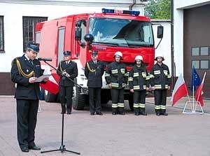 Załoga nowego wozu strażackiego, a przed mikrofonem komendant powiatowy PSP - mł. bryg. Krzysztof Hoffmann