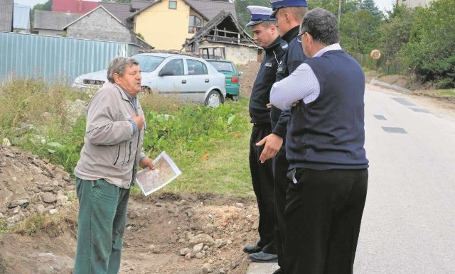 Jerzy Selega rozmawia z miechowskimi policjantami i Sławomirem Sendkiem, stojąc w rozpoczętym wykopie.