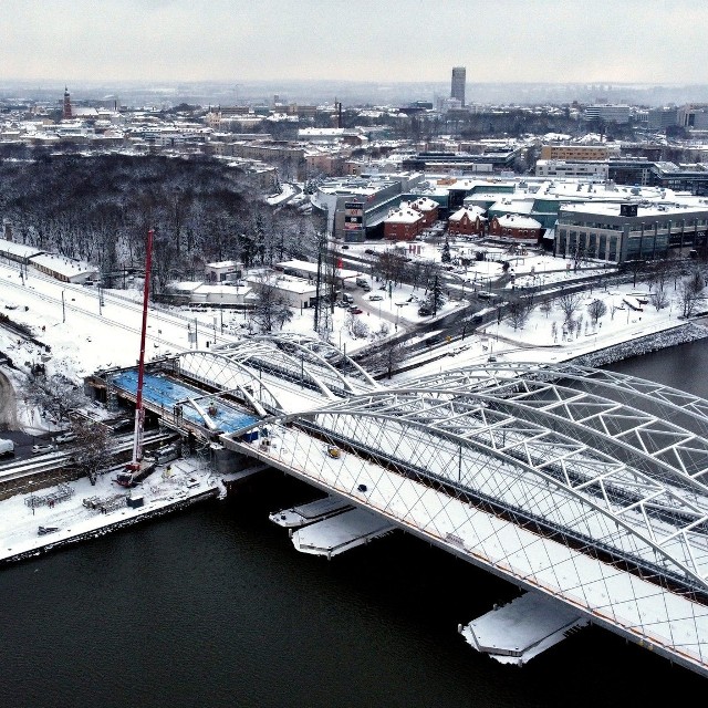 Na ostatnim przęśle budowanego mostu kolejowego nad Wisłą dojrzewa beton. Prace odbywają się w mroźnej, zimowej scenerii.