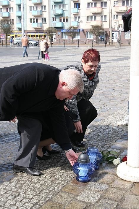 Prezydent Tadeusz Jędrzejczak pali znicz przy maszcie z flagą narodową