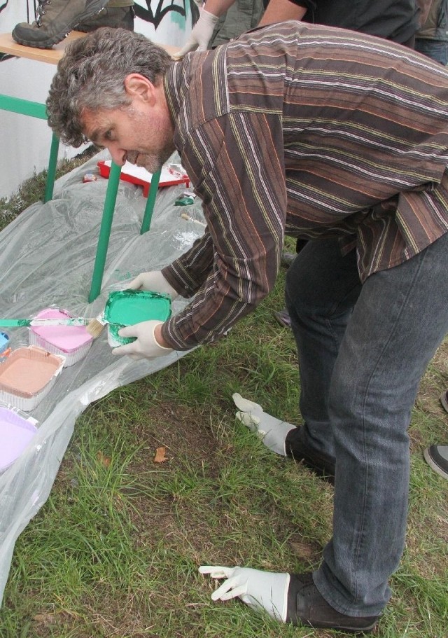 Senator Krzysztof Słoń maluje z ochroną rąk i nóg.