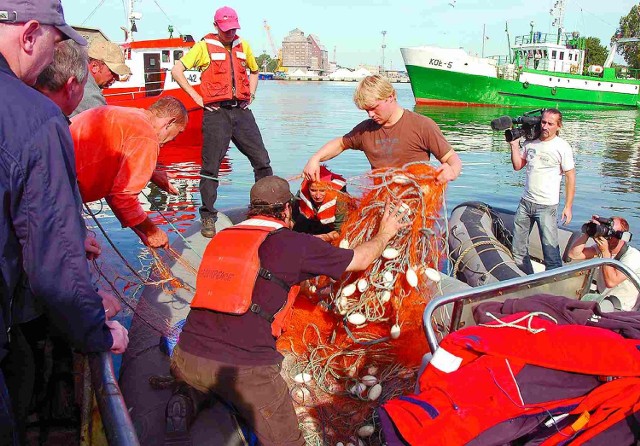 Młodzi ekolodzy z Greenpeace przekazują sporną sieć kołobrzeskiemu rybakowi.