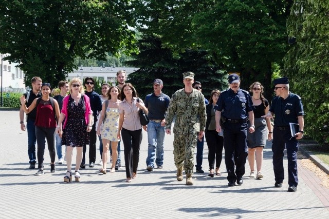 Amerykańscy studenci z Uniwersytetu Sam Houston w Huntsville (Texas) gościli przez dwa dni z wizytą w słupskiej Szkole Policji. Na co dzień młodzi Amerykanie są studentami kierunków związanych z wymiarem sprawiedliwości o specjalizacji prawa karnego.W trakcie wizyty w Słupsku, na zaproszenie Komendanta Szkoły insp. Jacka Gila, studenci mogli zapoznać się z historią polskiej Policji, która w tym roku obchodzić będzie swój jubileusz 100-lecia. Studenci zapoznali się z systemem kształcenia nowych policyjnych kadr, a także gościli w obiektach symulacyjnych obserwując wybrane zajęcia.Program pobytu przewidywał także omówienie roli policjantów w trakcie różnego rodzaju sytuacji kryzysowych i zdarzeń nadzwyczajnych, w tym także tych o charakterze terrorystycznym.O aspektach codziennej policyjnej służby na Pomorzu Środkowym opowiedział studentom Komendant Miejski Policji w Słupsku insp. Leszek Gurski. Program wizyty w policyjnej szkole przewidywał także amerykański akcent -  spotkanie z zastępcą dowódcy amerykańskiego komponentu Bazy w Redzikowie ppłk. Bradem M. Baer`em, który opowiadał między innymi o swojej służbie w US Navy i kontaktach z amerykańską Polonią w Chicago, które jest jego miastem rodzinnym.W drugim dniu wizyty studenci mieli możliwość zapoznania się z w wybranymi elementami policyjnego wyposażenia, a także obserwacji, w jednym z obiektów symulacyjnych, przygotowanej specjalnie dla nich, interwencji policyjnej wobec uzbrojonego przestępcy, który wziął zakładnika. Amerykanie mieli także możliwość oddania strzałów z amunicji ćwiczebnej sytemu FX Simmunition, który wykorzystywany jest również w procesie szkolenia funkcjonariuszy amerykańskich.Na zakończenie drugiego dnia wizyty w policyjnej Szkole studenci pojechali również do ratusza miejskiego przy placu Zwycięstwa, gdzie zwiedzili neogotycką budowlę, podziwiali panoramę miasta z ratuszowej wieży. Rozmawiali także z Prezydent miasta Krystyną Danilecką-Wojewódzką i jej zastępcą Markiem Golińskim. Na zakończenie pobytu w ratuszu opiekunka grupy prof.nadzw. SH Magdalena Denham wraz z przedstawicielem studentów wręczyła wiceprezydentowi Słupska Markowi Golińskiem specjalną amerykańską Flagę Bohaterów, na której umieszczono nazwiska funkcjonariuszy służb, którzy zginęli podczas akcji ratowniczej po ataku na World Trade Center.Zakończeniem całego drugiego dnia pobytu na Pomorzu Środkowym była wizyta w Centralnym Ośrodku Szkolenia Straży Granicznej w Koszalinie, gdzie omówiono główne zadania formacji oraz specyfikę ochrony zewnętrznej granicy Unii Europejskiej, w tym także funkcjonowanie Europejskiej Agencji Straży Granicznej i Przybrzeżnej FRONTEX. Studenci zapoznali się również z historią Straży Granicznej zwiedzając Sali Historii COSSG.Zobacz także: Dowóddca bazy w redzikowie w słupskiej szkole