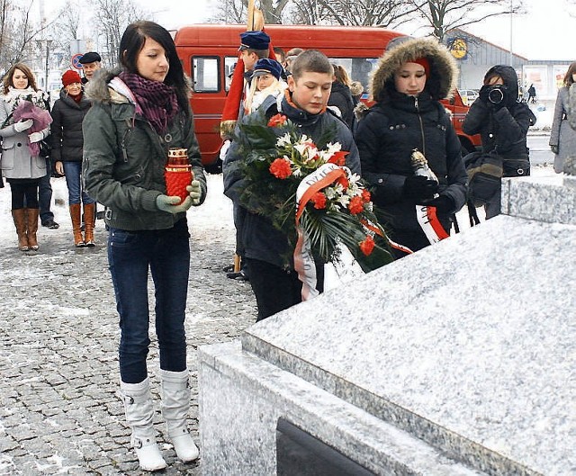 Malwina Frymarska, Adam Krzyżanowski i Renata MIchalska z Gimnazjum nr 9 składają kwiaty pod tablicą przy al. Chopina