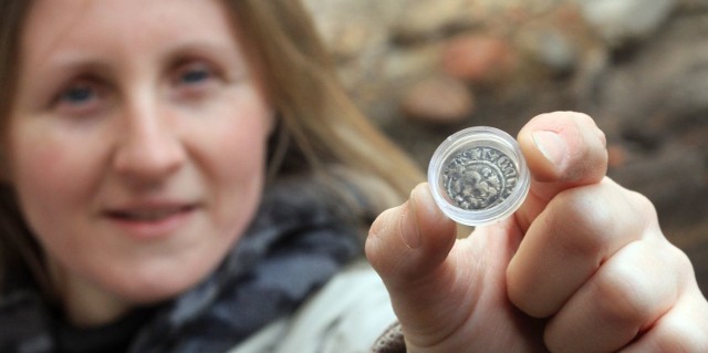 Archeolog Anna Siwiak prezentuje srebrny kwartnik z królem Kazimierzem Wielkim na awersie.