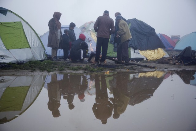 Migranci gromadzą się wokół ognia w pobliżu północnej granicy Grecji.