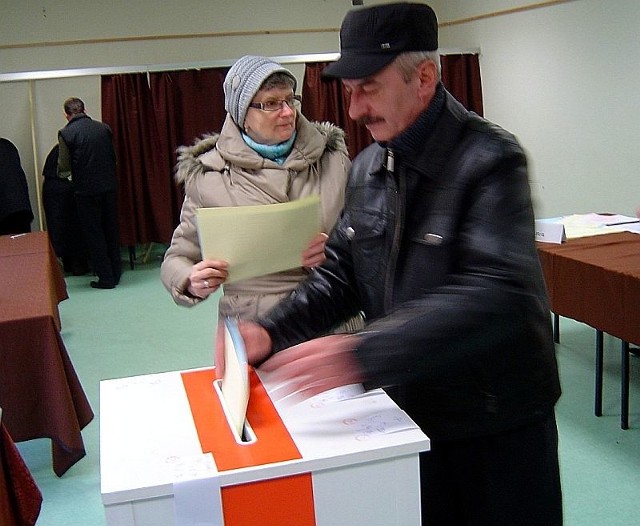 Mieszkańcy Opatowa do urny wrzucają karty do głosowania.