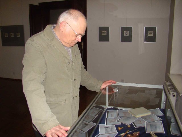Wojciech Łuczak, podczas swojej ostatniej wystawy w inowrocławskim muzeum w 2013 roku, nad gablotą z tworzywem i narzędziami jego miedziorytniczej pracy