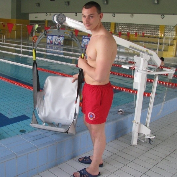 Ratownik, Maciej Wójt demonstruje specjalistyczną windę dla osób niepełnosprawnych na basenie w Krapkowicach.