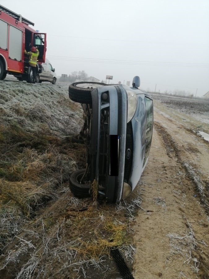 Na poboczu drogi leżał przewrócony samochód marki Ford, a w...