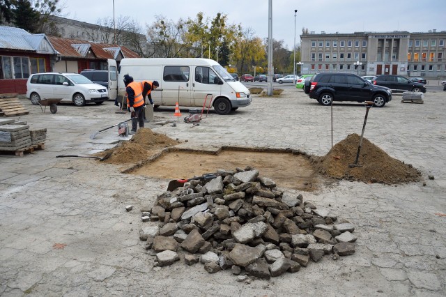 Pokruszone płyty chodnikowe są składane na stertę, w ich miejsce na placu kładzione są stare, ale całe płyty chodnikowe