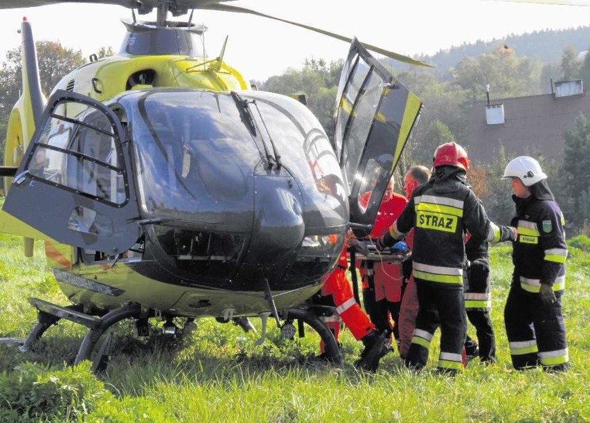 Strażacy pomagają w transporcie rannego do helikoptera