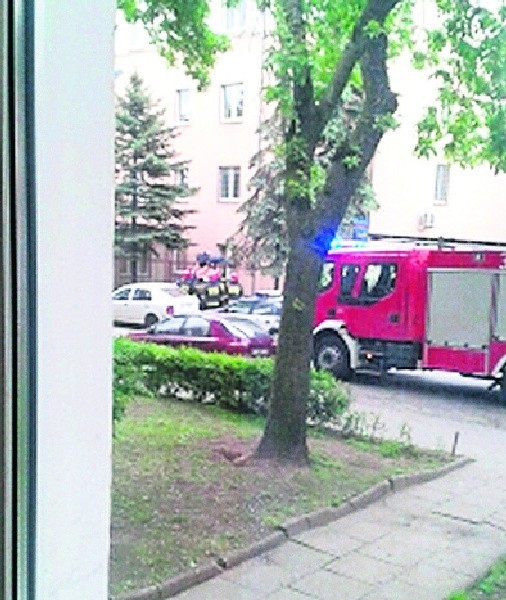 Strażacy pomagają ściągnąć rannego mężczyznę z metalowego ogrodzenia przed komisariatem policji przy ul. Ciesielskiej.