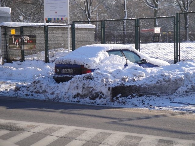 Śnieg spychany jest na samochody.