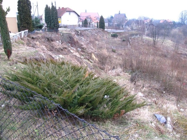 Ziemia osunęła się zabierając fragment drogi i szkolne boisko. W tle (biała) szkoła.